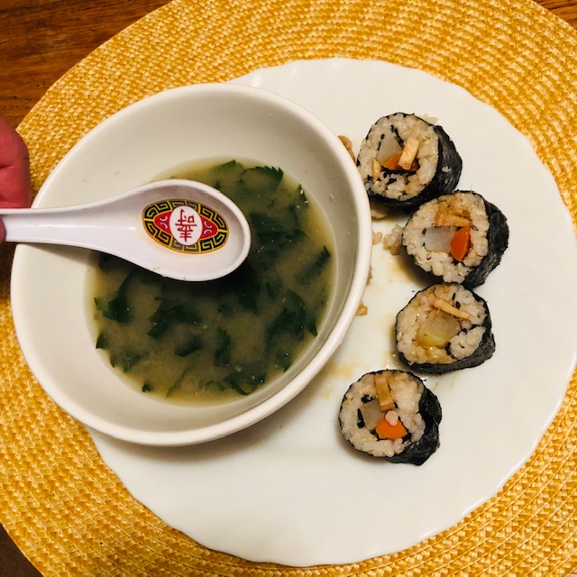 Plate with four slices of daikon-carrot sushi and a bowl of miso and nettles soup